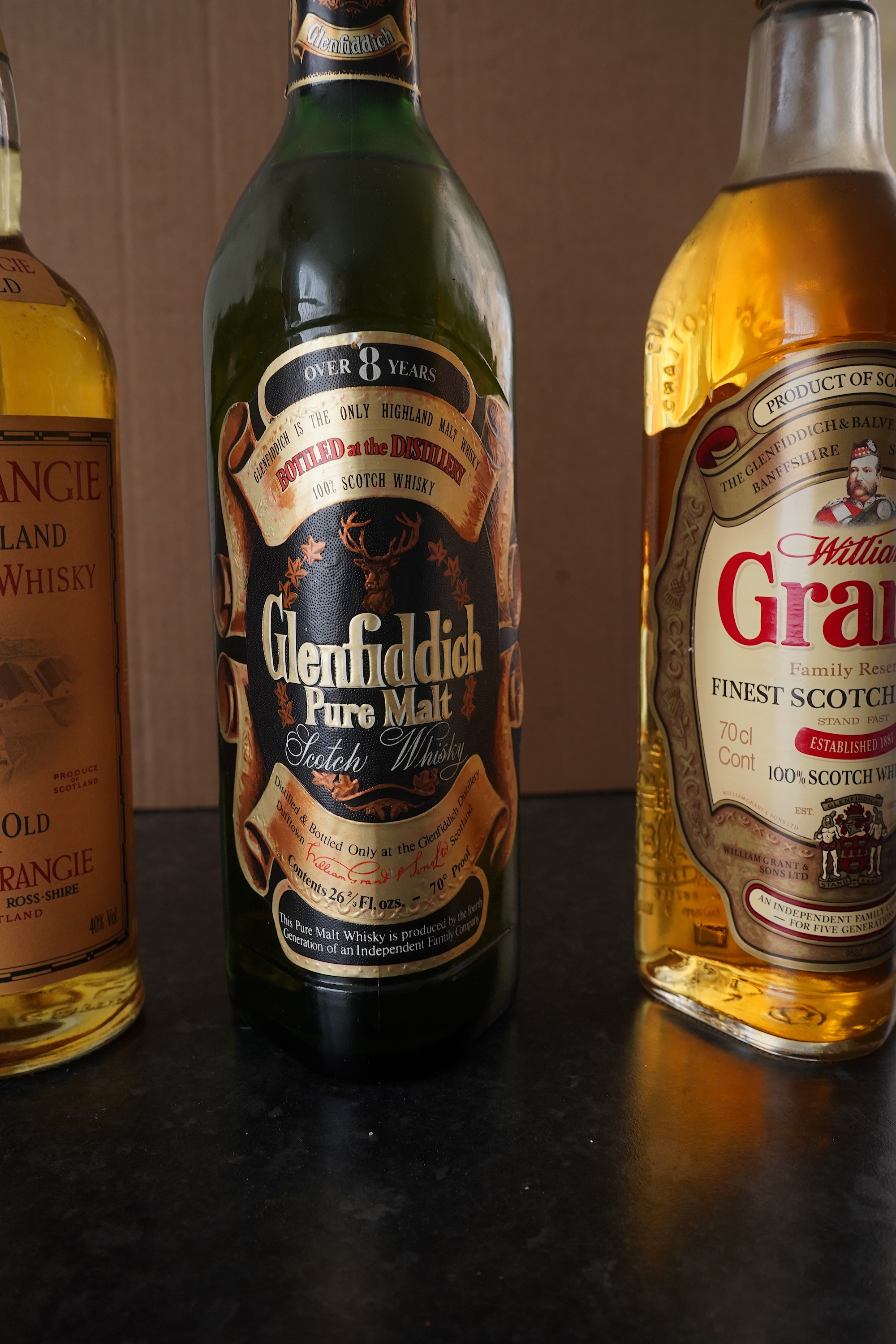 Three bottles of malt whisky: Glenmorangie, Glenfiddich and Grants